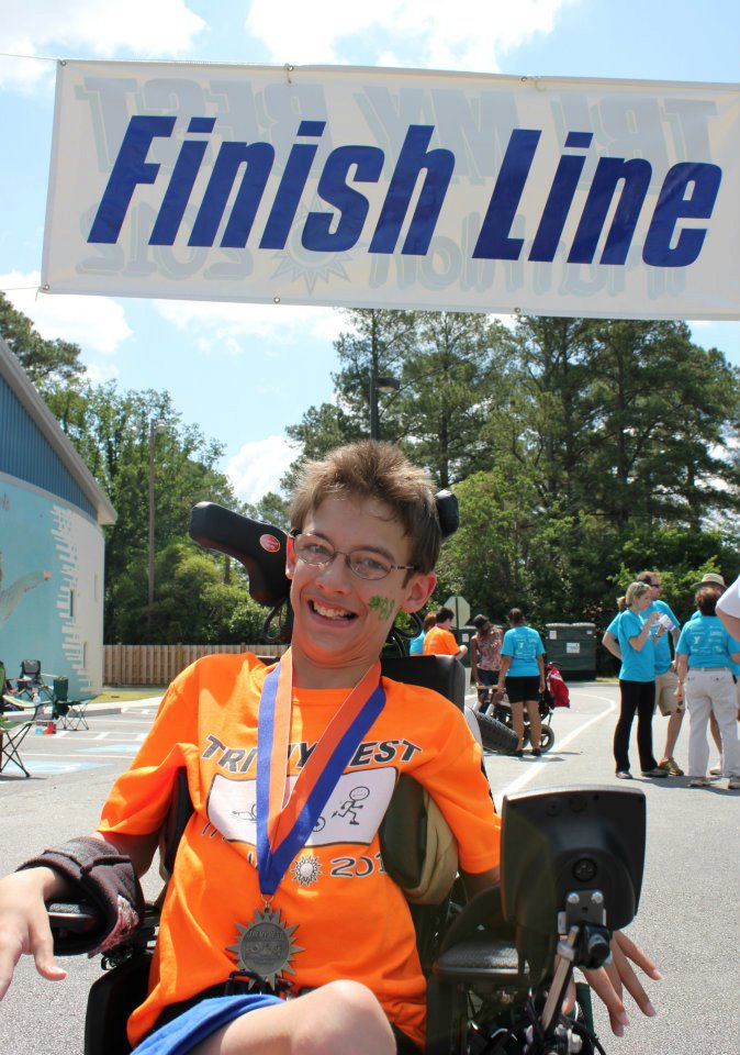 Young teenager in a wheelchair smiles at the finish line of a race