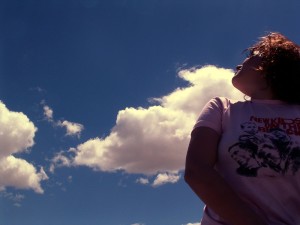 Girl looks up at a blue sky