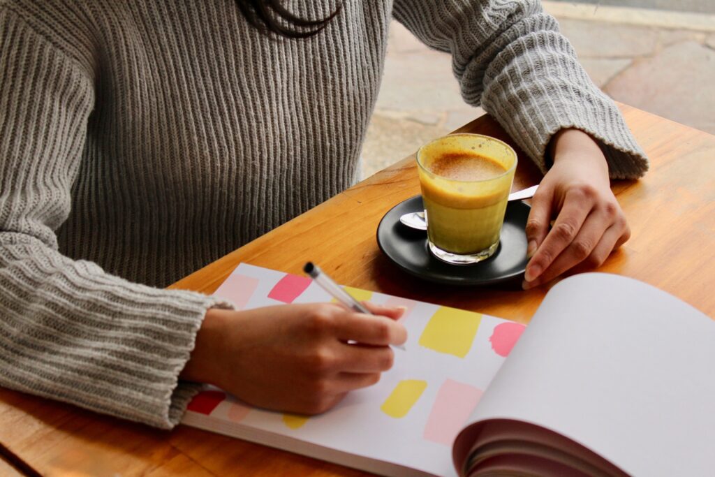 Woman sitting at a desk with a coffee and journal