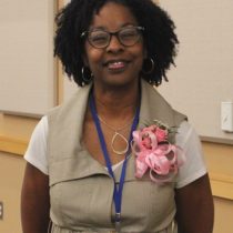 Black woman stands smiling wearing a coursage