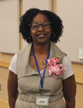 Black woman stands smiling wearing a coursage